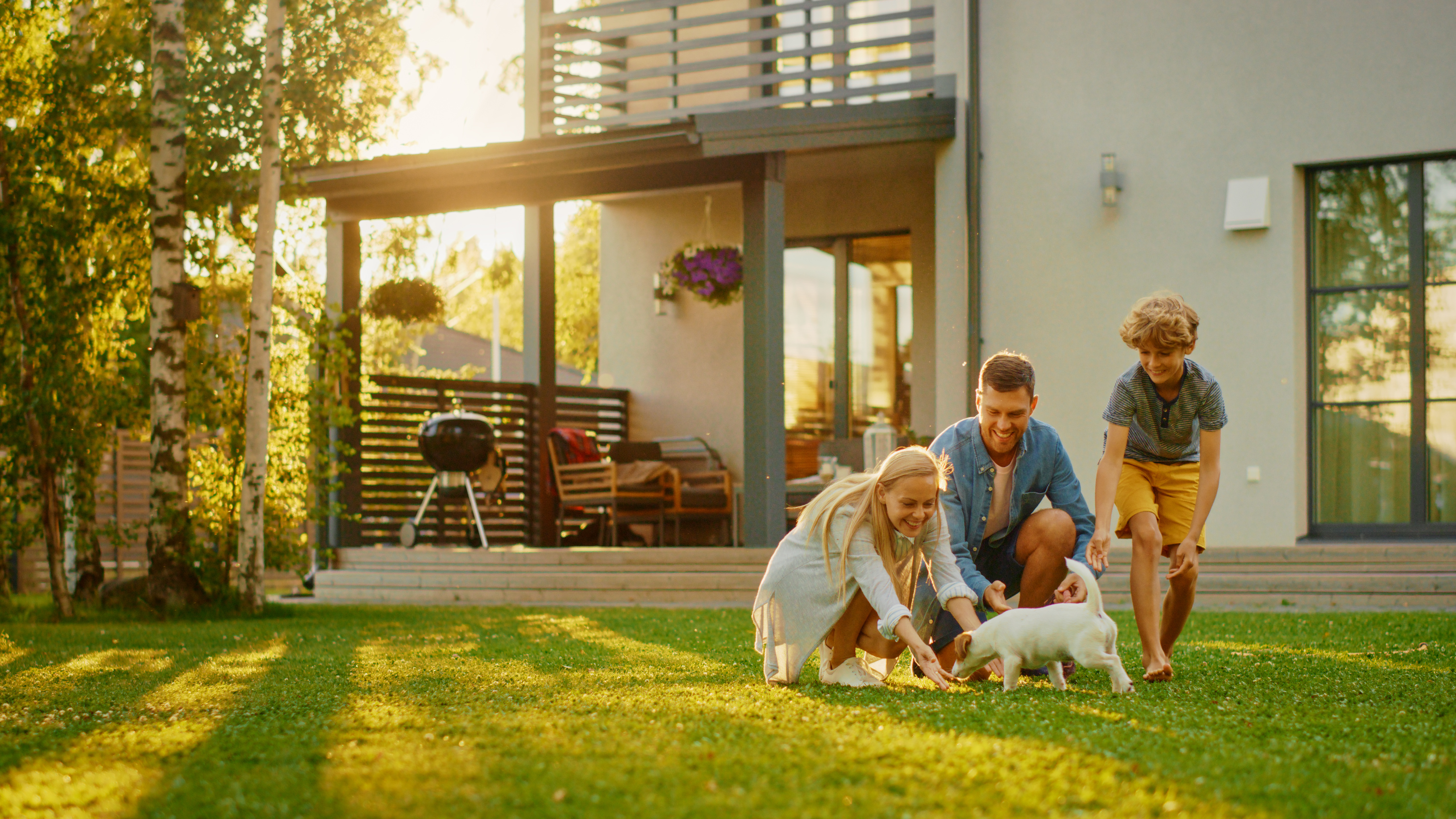 Familie in de tuin met de zon op de achtergrond en hun huis wachtend op uitsluistel van de Eerste Kamer over de salderingsregeling