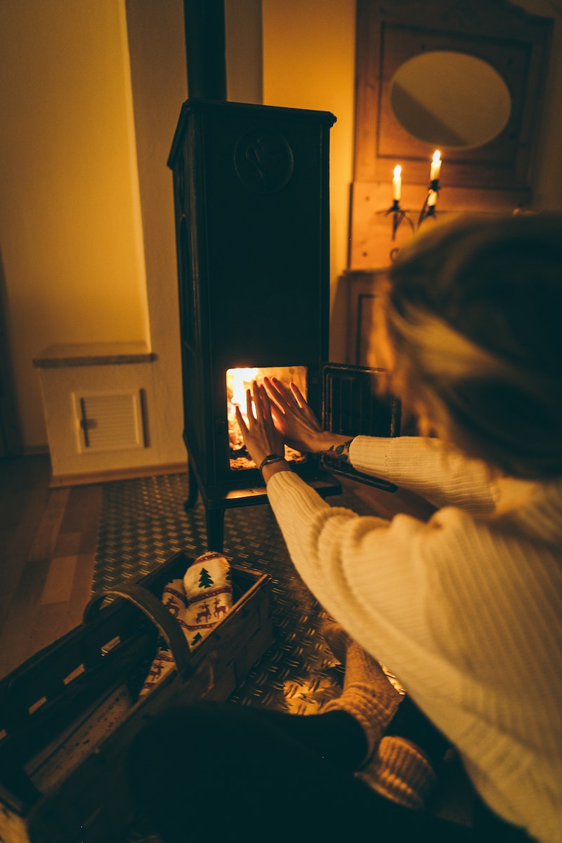 Vrouw zittend voor pellet kachel.